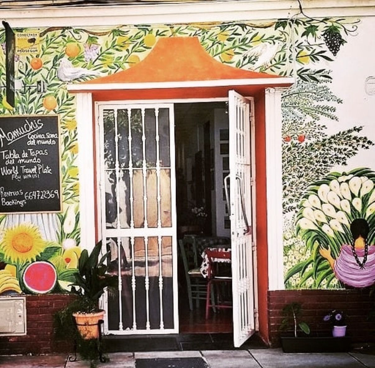 The Mamuchis doorway, surrounded by a painted mural of fruit trees, sunflowers and a woman carrying calla lilies